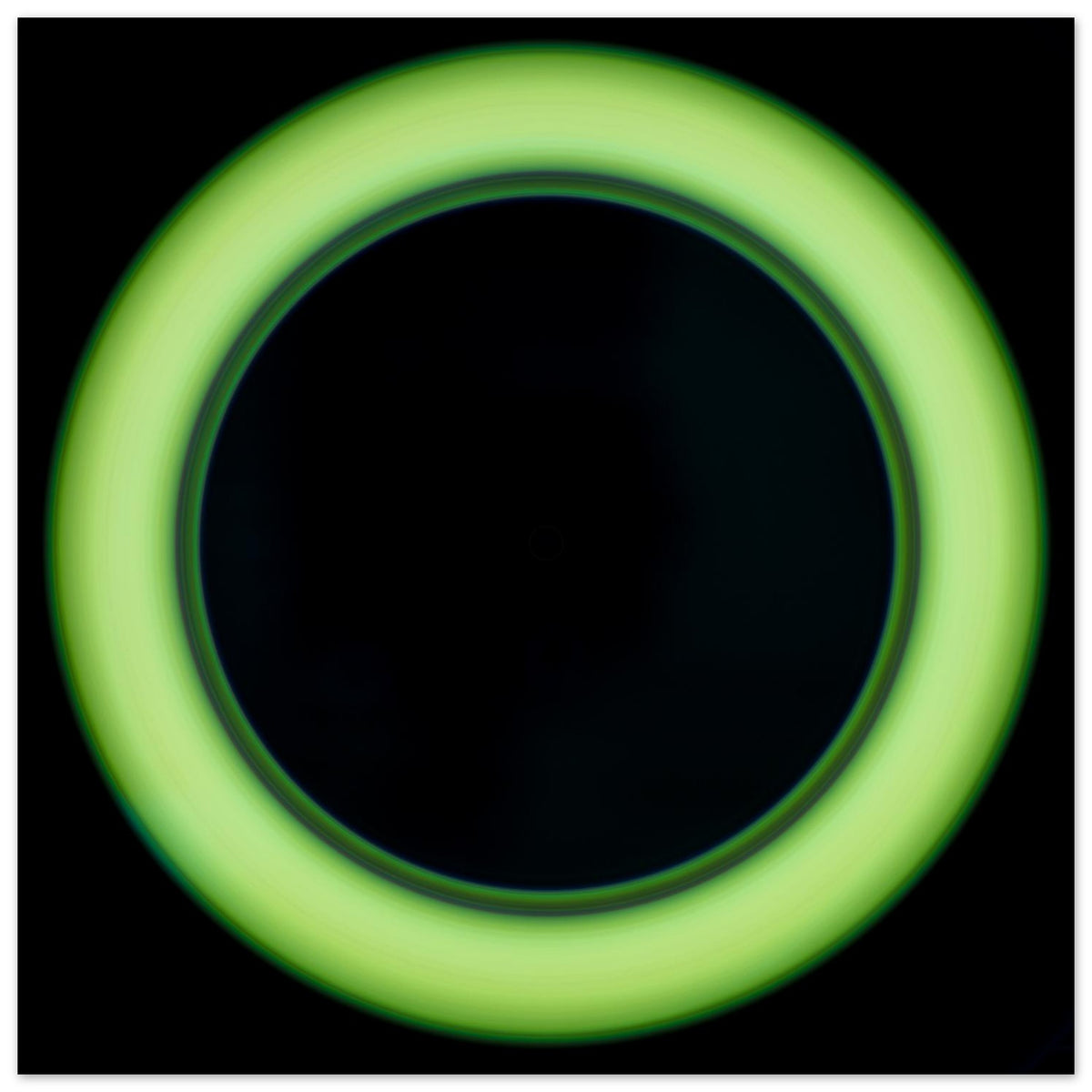 A bright lime green circular ring shape with a large black center and soft glowing edges against a black background.